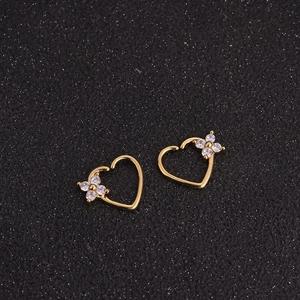 Macro shot of gold heart earrings featuring a crystal-set four-leaf clover design