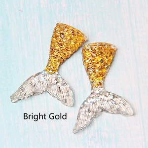 Detail of two resin mermaid tails in bright gold and transparent silver glitter