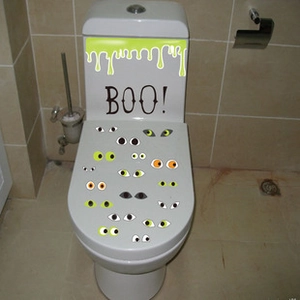 Close-up of Halloween toilet stickers with green slime drips and 'BOO!' text design