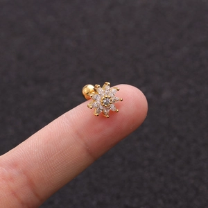 Golden sunflower stud earrings with zircon crystals and screw back shown on fingertip