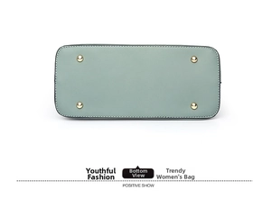 Detail of light green leather bag bottom with four protective gold metal feet studs