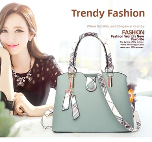 Detail of light green PU leather tote bag with plaid handles and a heart charm accessory