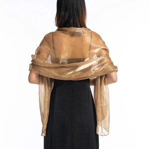 Rear view of an elegant sheer gold shawl with a glossy finish draped over black dress