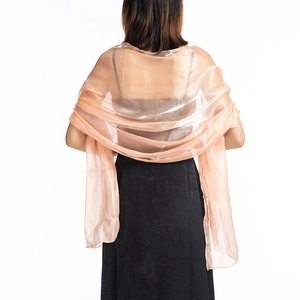 Detail of sheer peach bridal shawl draped over shoulders on a black dress