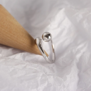 Close-up of minimalist S925 sterling silver ring with smooth bead on a display stand