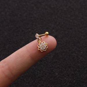 Detailed close-up of a tiny gold star earring with clear zircon inlay on a fingertip