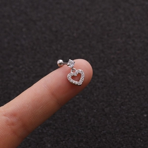 Macro shot of a silver steel cartilage stud with micro-pave heart charm on a fingertip