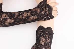 Close-up of black lace fingerless gloves with delicate rose embroidery and wavy edges