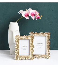 Detail of vintage gold leaf texture photo frames in sizes 10x15cm and 13x18cm on white table