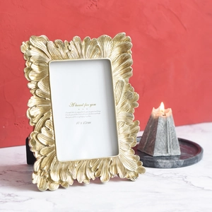 Vintage golden photo frame with embossed feather patterns and elegant desktop decor