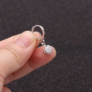 Macro shot of silver sunflower zircon earrings with a sparkling star snowflake charm