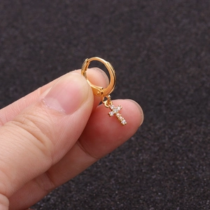 Close-up of gold-plated cross earring with cubic zirconia stones worn on ear