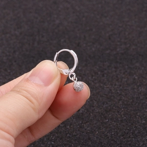 Macro view of silver sunflower hoop earring with micro-set zircons on dark background