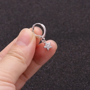 Close-up of silver star huggie earring with micro-paved zircons held by hand