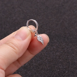 Detailed view of silver hoop earring with crystal winged pendant held by hand