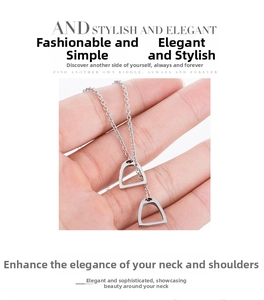 Vue macro d'un collier avec pendentif fer à cheval argenté tenu à la main en détail