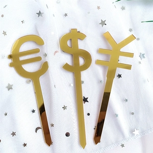 Detailed view of three golden acrylic cake toppers featuring currency signs on white gauze