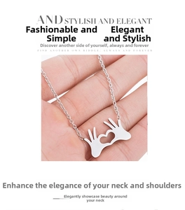 Macro detail of silver OK gesture heart pendant necklace on minimalist chain