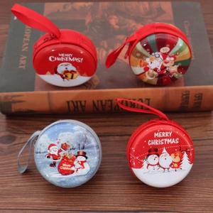 Christmas tinplate coin purses with festive patterns and zippers on a wooden background