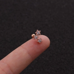 Macro view of rose gold triple star stud earrings with zircon held by fingers
