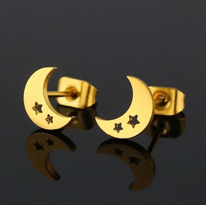 Macro view of gold moon and star stud earrings with mirror finish on black surface