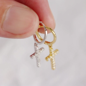 Macro detail of gold and silver S925 sterling silver cross hoop earrings with crystals