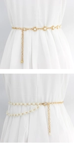 Detail view of a gold-finish pearl waist chain styled on a white dress for women