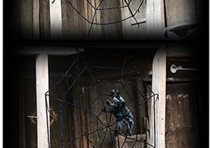 Close-up of a giant black spider web with realistic plush spider on old wooden structure