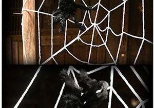 Close-up of a giant black fuzzy spider toy climbing a thick white rope spider web