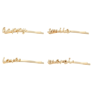 Detailed close-up of 4 gold metal hair clips featuring happy, smile, love, and merci scripts