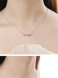Close-up of heart-arrow pendant with pink strawberry quartz and silver chain