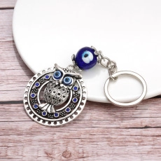 Close-up of silver owl charm with blue evil eye bead and intricate blue crystal inlay