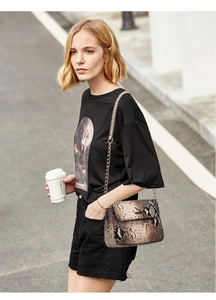 Detailed view of snake skin pattern shoulder bag with elegant metal chain strap and flap