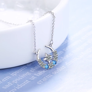 Silver star and moon pendant necklace with blue and white crystals on a dainty chain