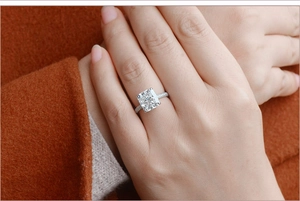 Elegant cushion cut moissanite ring with pavé band worn on a model hand with red sleeve