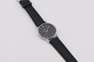 Detail of minimalist black dial men's quartz watch with silver case and leather strap