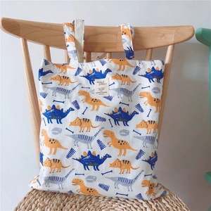 Detail of canvas tote bag with colorful dinosaur prints and a central fabric patch