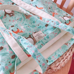 Close-up of mint green floral canvas tote bag with forest animal print and fabric label