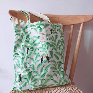 Detail of canvas tote bag featuring tropical palm leaves and toucan bird pattern