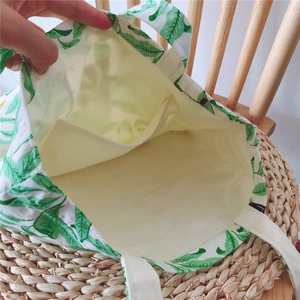 Detail view of cotton shopping bag interior featuring green leaf pattern and inner pocket