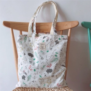 Detail of floral animal print on cream canvas tote bag hanging on a wooden chair
