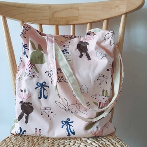 Detailed shot of pink cotton tote bag with rabbit patterns on a wooden chair