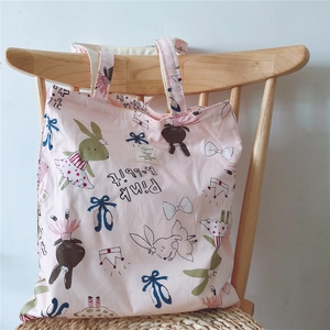 Detail of pink cotton tote bag featuring cute rabbit illustrations on a wooden chair