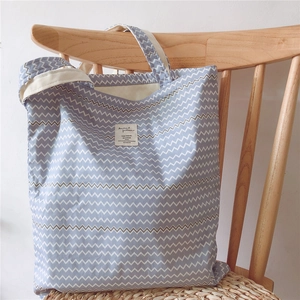 Close-up of blue and white zigzag pattern canvas tote bag hanging on wooden chair
