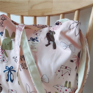Detailed view of pink floral cotton tote bag with cartoon patterns on wooden chair