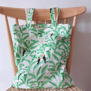 Detail of canvas tote bag with toucan print hanging on a wooden chair