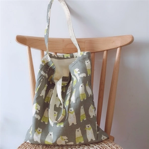 Detail of grey cotton tote bag featuring cute polar bear prints on a wooden chair