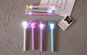 Dettaglio di quattro penne luminose colorate con unicorni e orsetti su una scrivania