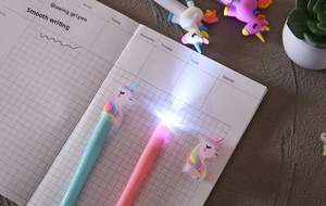 Primo piano di quattro penne gel unicorno luminose in colori pastello su un taccuino