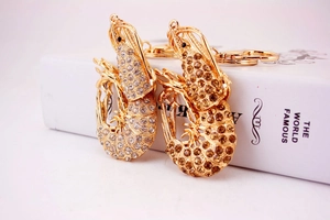 Detail of gold metal lobster keychain featuring clear and amber rhinestones inlay